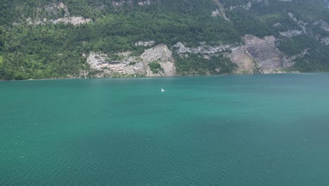 wide angle shot of lonely yacht sailing in turquoise waters of swiss lake