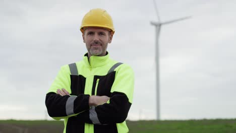 portrait of caucasian professional man standing on wind turbine field.