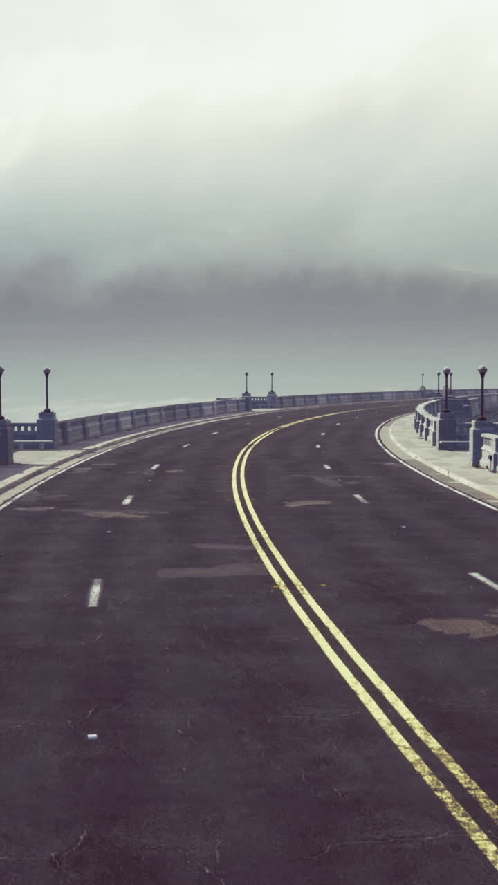 Foggy morning on a winding road at a coastal bridge in a serene landscape