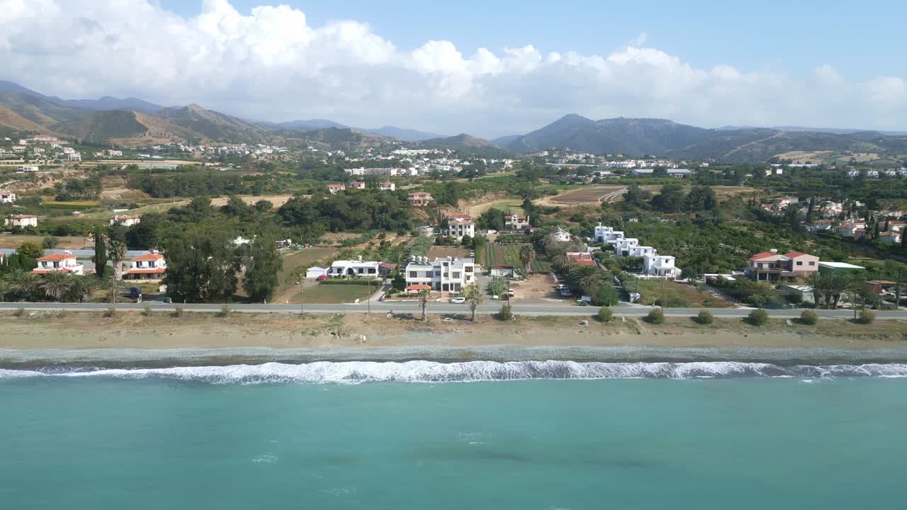 bahía de chrysochus en chipre con olas que golpean la costa, colinas verdes en el fondo, vista aérea