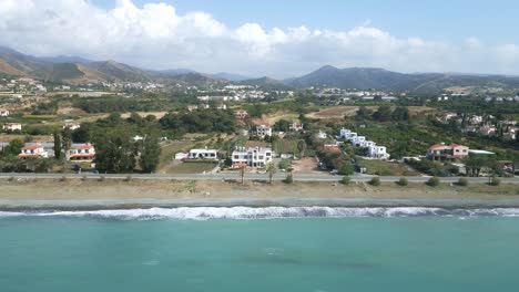 Chrysochous-bay-in-cyprus-with-waves-hitting-the-shore,-green-hills-in-the-background,-aerial-view