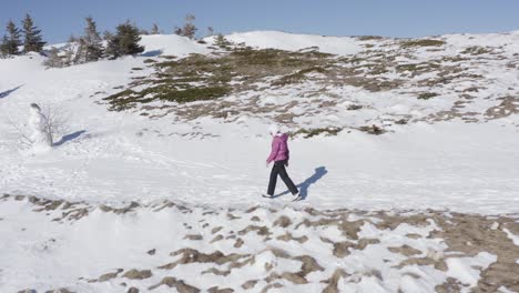 Woman-walks-in-winter-heavily-dressed-in-mountains-covered-with-snow