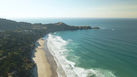 Wide-drone-shot-of-waves-rolling-into-the-Oregon-coast-on-a-sunny-day