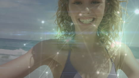 glowing network of connections against portrait of caucasian woman blowing a kiss at the beach