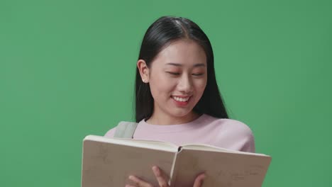 happy asian woman student reading book in green screen studio