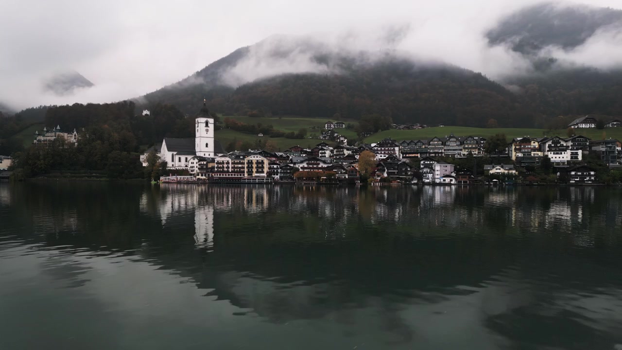 Bevægelig droneoptagelse af Wolfgang am Wolfgangsee på en regnvejrsdag tæt på søen.