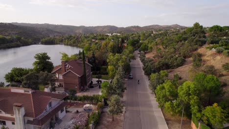 una carretilla aérea que revela a un automovilista que pasa por una carretera residencial de villas con las manos levantadas