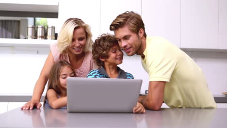 Familia-Mirando-La-Computadora-Portátil-En-La-Cocina