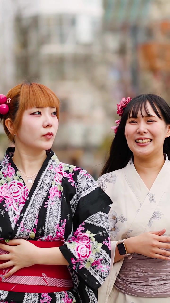 Smilende japanske kvinner iført tradisjonell blomsterkimono går gjennom en bygata i Harajuku, Tokyo