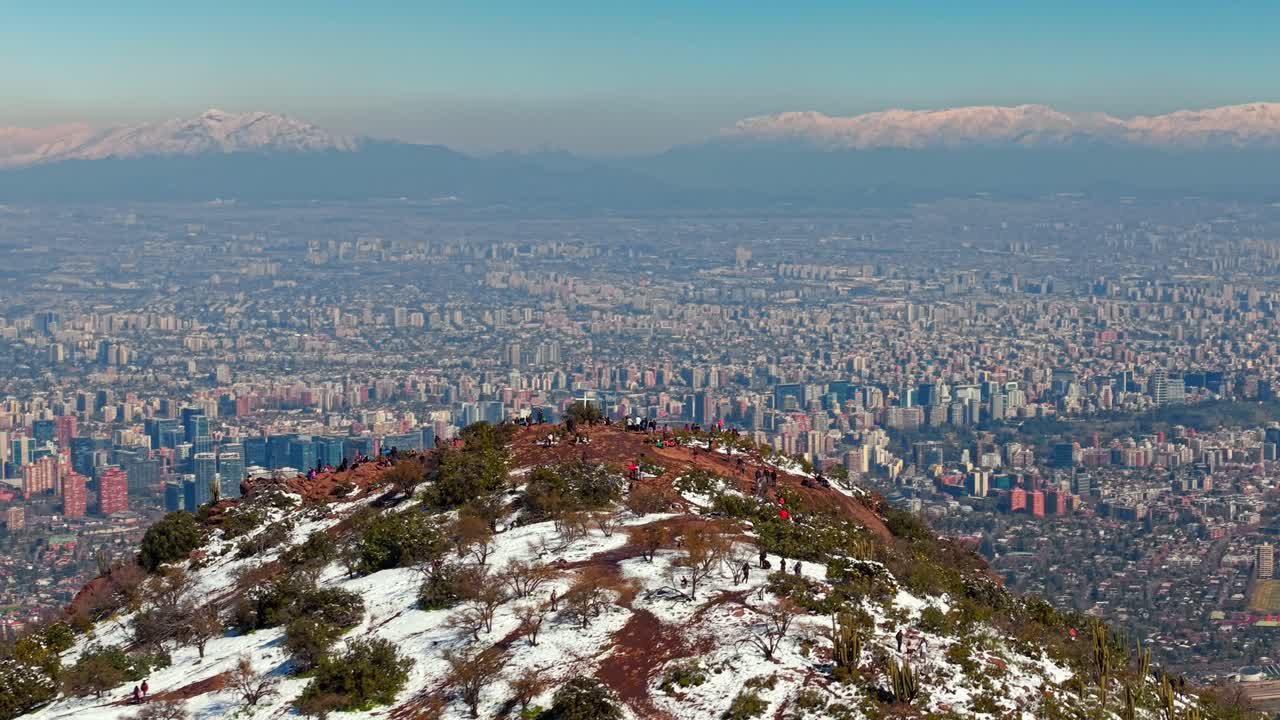 A hilltop cross with Santiago Nevado in the distance and the city slowly unfolding below