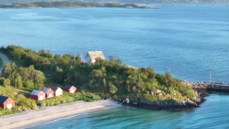 typical norwegian house facing the beach and blue sea in summer in bovaer, senja, norway