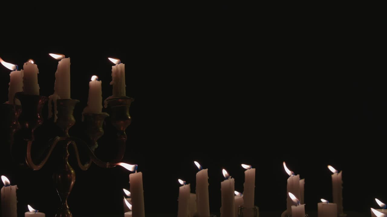un grupo de velas blancas, algunas en un candelabro, encendidas y funcionando durante un tiempo