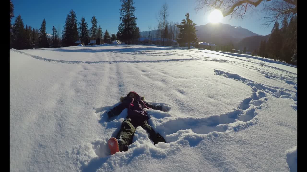 niño haciendo ángeles de nieve en la nieve durante el invierno 4k