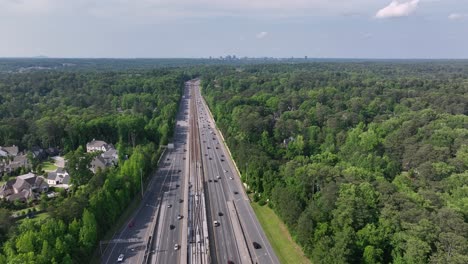 cinematic drone shot of atlanta city interstate highway traffic, georgia state route driving through park, usa