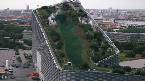 wide aerial retreating shot of family skiing down copenhill slope, copenhagen