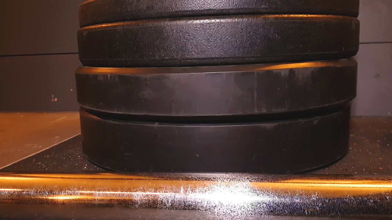 олимпийская штанга и бамперные плиты на полу в коммерческом тренажерном зале