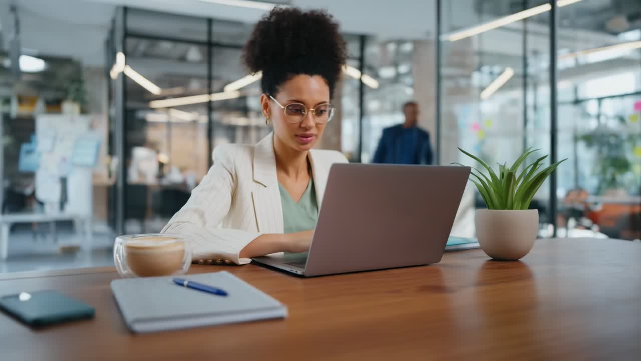 Side angle of a professional woman working on a laptop in a modern office, video call setup