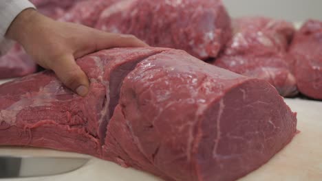 butcher cuts fresh raw bull meat in half with knife, slow motion closeup