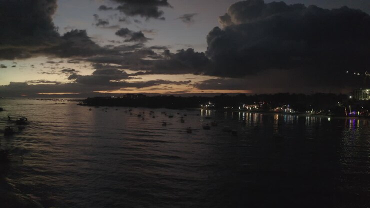 Cinematic sunset drone shot over the ocean with boats in the frame and reflections along the shoreline, Aerial, Philippines, Asia