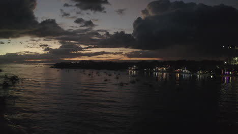 avión no tripulado cinematográfico al atardecer filmado sobre el océano con barcos en el marco y reflejos a lo largo de la costa, aérea, filipinas, asia