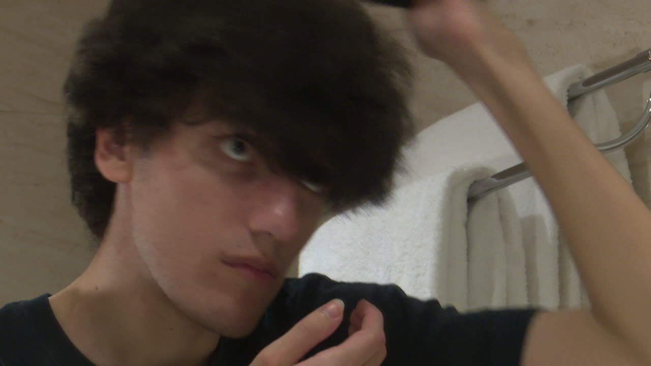 Young Man Combing His Hair in Bathroom