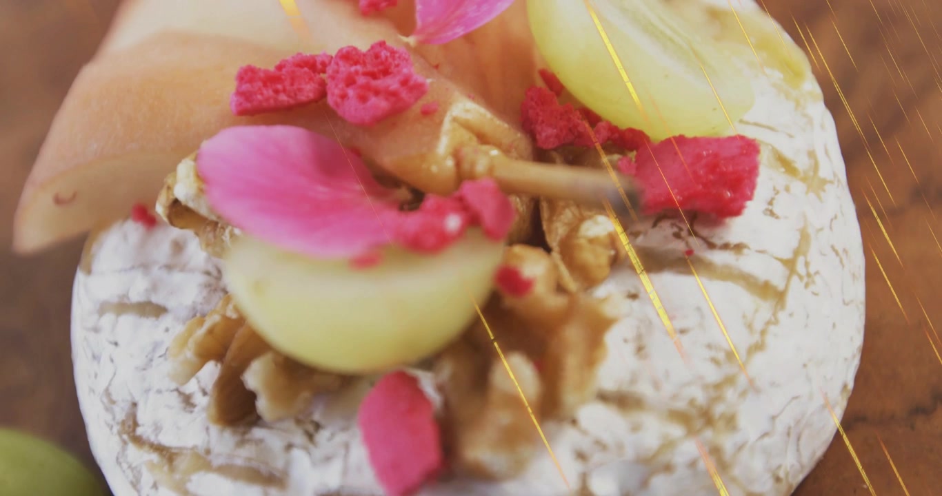 Camera pushing in with gold streaks revealing cheese topped with grapes, nuts to highlight garnish