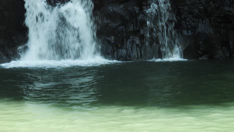 Handheld-shot-of-a-waterfall-on-bali-in-ubud-indonesia-with-view-of-the-dark-rocks-in-the-middle-of-the-jungle