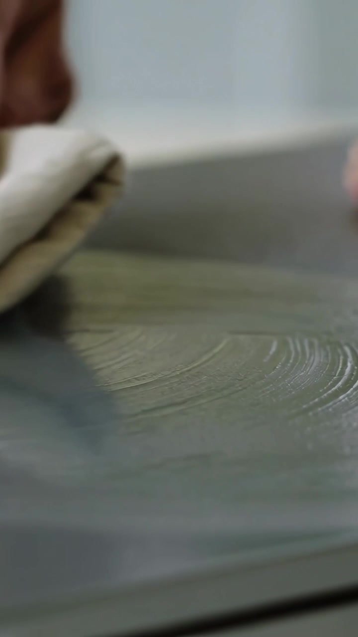 Vertical video: Pressing white cotton cloth, hand wiping dark counter at home clearing smudges
