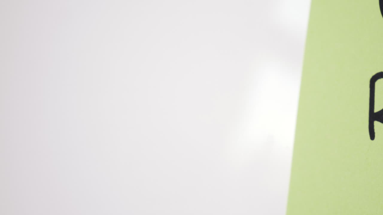 Pan reveal of ROI text on green note held by magnet on whiteboard with selective focus