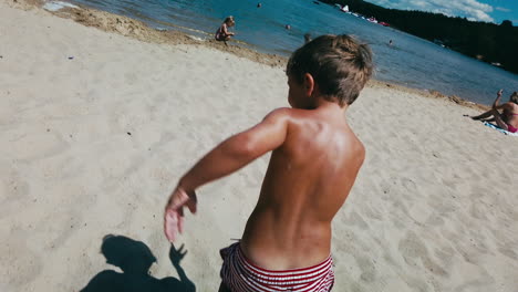 POV,-Während-Die-Kamera-Den-Kleinen-Jungen-An-Einem-Sommertag-An-Einem-Sandstrand-Herumjagt