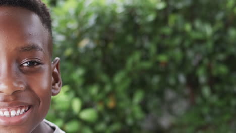 african american boy smiles in a sunny outdoor setting with copy space