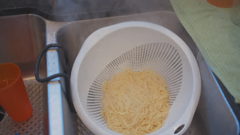 straining spaghetti in a sink