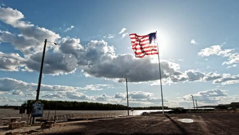 bandera estadounidense ondeando en el viento frente al sol brillante a lo largo del río mississippi en grafton, illinois, ee.uu.