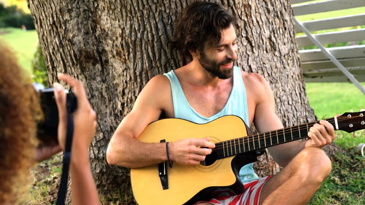 기타 를 연주 하는 남자 의 사진 을 찍고 있는 여자