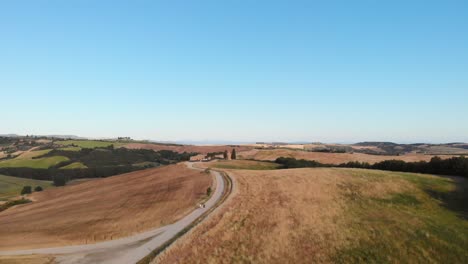 Toma-Aérea-De-Colinas-Y-Valles-En-La-Luz-Dorada-Del-Atardecer,-Val-D&#39;orcia,-Toscana,-Italia