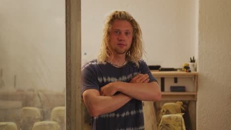 portrait of caucasian male surfboard maker standing with his arms crossed and looking at camera