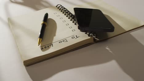 video of notebook with to do list and copy space, smartphone and pen on wooden surface