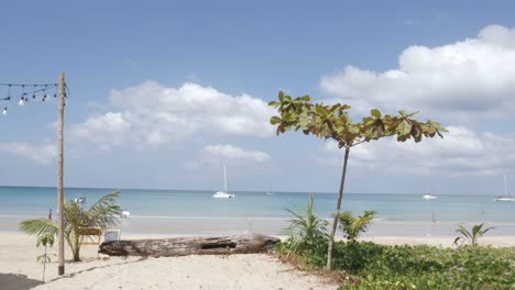 the-beach-with-a-few-yachts-in-sea,-white-sand-and-wave-from-peaceful-sea-in-sunshine-daytime