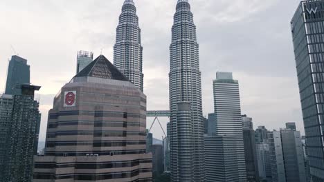 drone rises close to skyscraper silver buildings of kl malaysia on cloudy skyline
