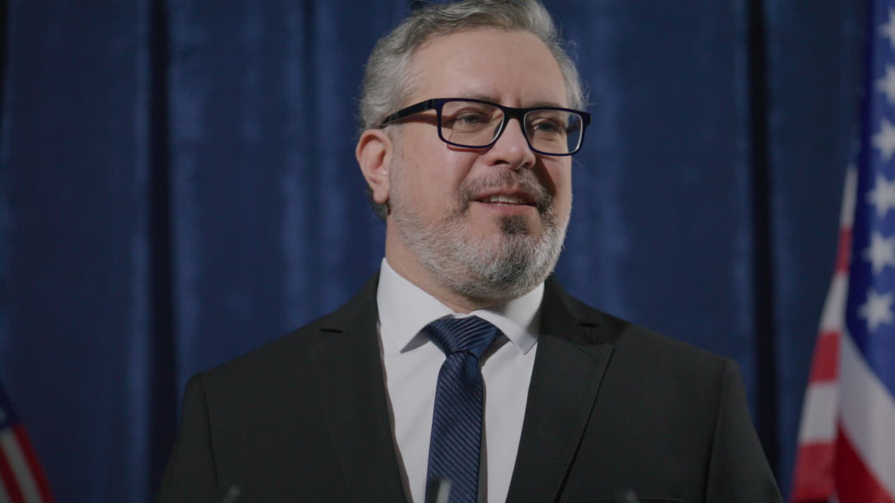 Politician Speaking during Press Conference with US Flags in Background