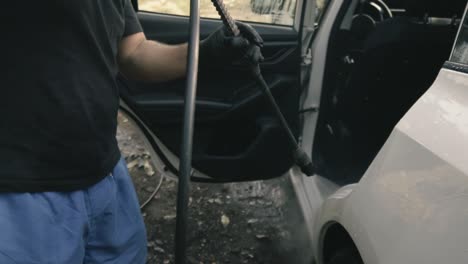 male cleaning a white car with a pressure washer