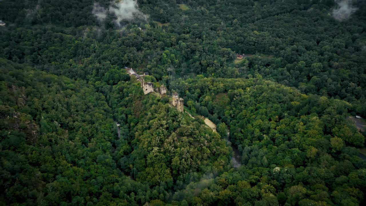 wide drone view of a wild valley with an abandoned castle surrounded by a river