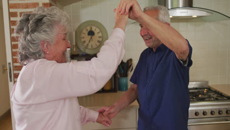pareja caucásica de alto nivel bailando en la cocina en cámara lenta