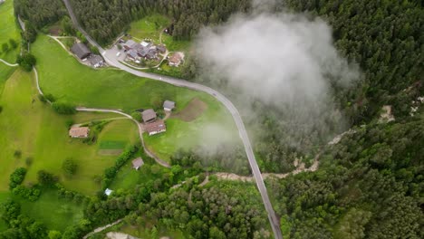 Cinematic-establishing-shot-of-long-road-between-green-vegetation-and-trees---Eagle-Eye-View-above-clouds