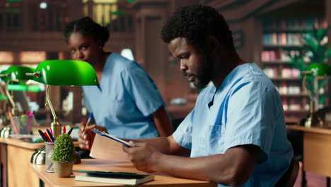 medical assistant student reading under a green lamp in the library