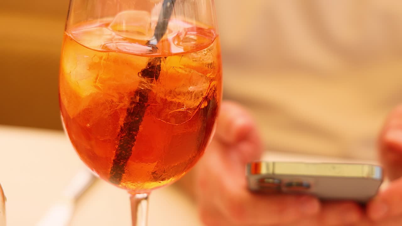 Aperol Spritz mit einer Person, die ein Smartphone benutzt