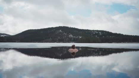 Vista-Trasera-De-Un-Hombre-Disfrutando-Del-Agua-Fría-En-El-Lago-Mientras-Contempla-La-Montaña