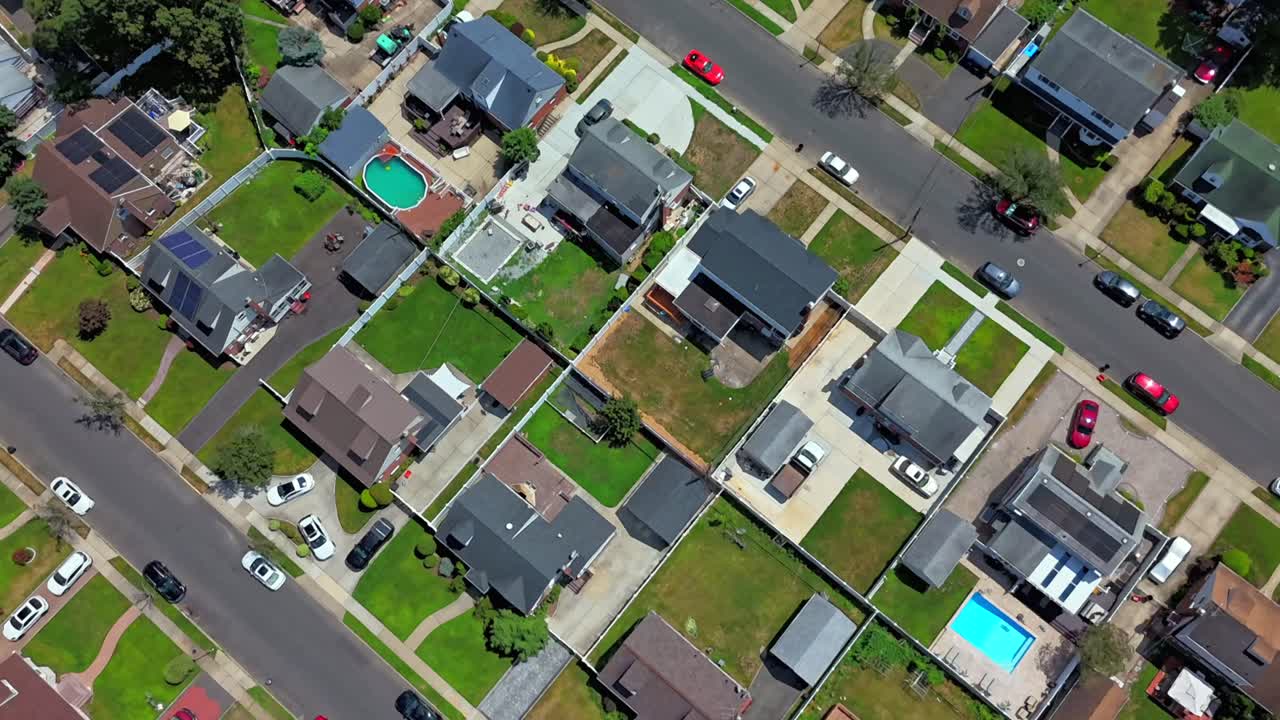 An aerial time lapse over suburban neighborhood by the Southern State Parkway during a sunny day. Flying over the houses on Long Island, the camera dolly out and tilt straight down