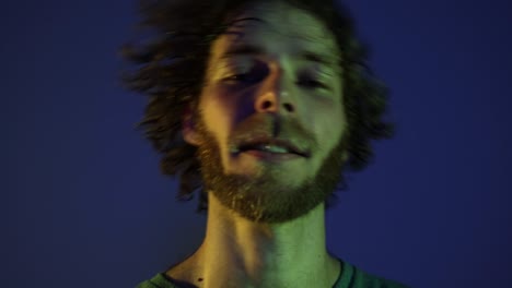 back view of hairy young man shaking his head isolated over dark blue background in neon light. modern dance art, fashion, youth, ad, style. 4k, video. closeup