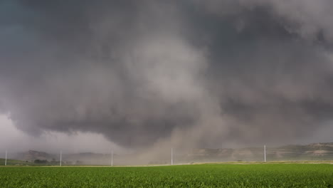 dust lifted by strong stormy winds blow across fields under dark storm clouds